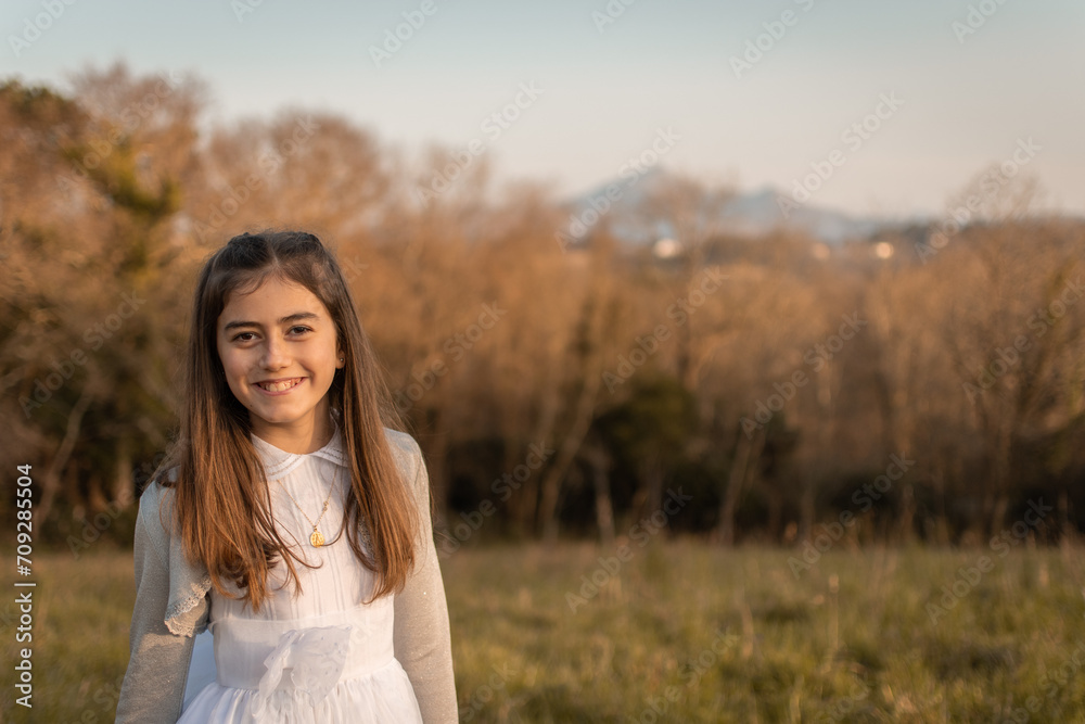 Sweet and smiling girl celebrating her communion with her first communion dress while enjoying nature and the countryside, image with right copyspace Sweet and smiling girl celebrating her communion with her first communion dress while enjoying nature and the countryside, image with right copyspace