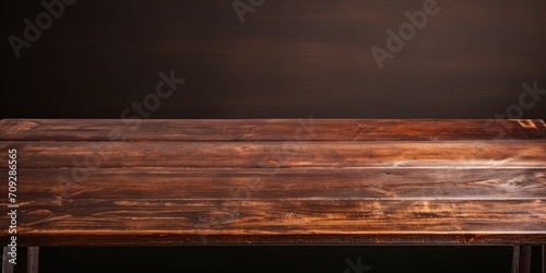 Worn old wooden table with dark brown background.