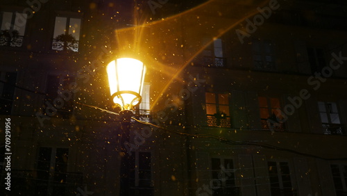 Un lampadaire éclairant une zone dans l'obscurité, avec quelques reflets de lumière et d'ombre, de neige ou d'hiver, solitude, ambiance sombre, effet photographique, environnement parisien