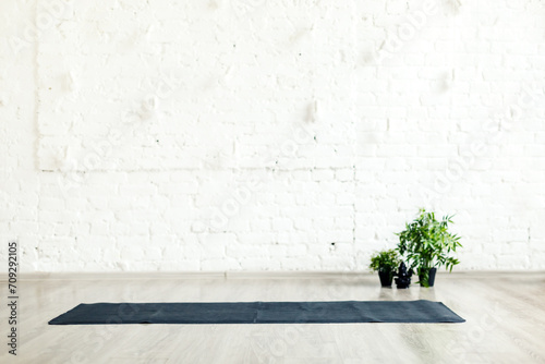 Unrolled yoga mat laid on the floor in empty space with white brick wall background photo