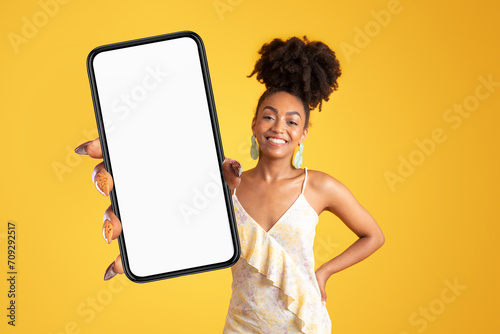 Cheerful young african american woman in dress hold smartphone © Prostock-studio