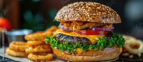 Tasty cheeseburger on table with onion rings.