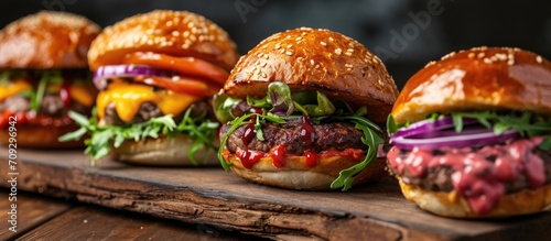 Assorted options of filling with colorful hamburgers on wooden board, viewed from the side. © AkuAku