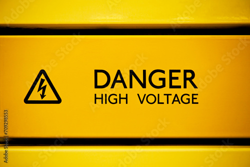 Close up of black danger high voltage sign on yellow background photo