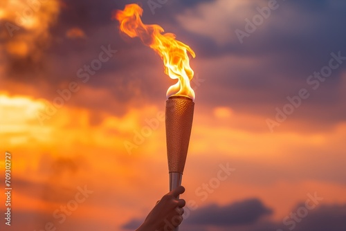 A hand holds the Olympic flame against the sky, a torch in his hand is a symbol of the international sports games