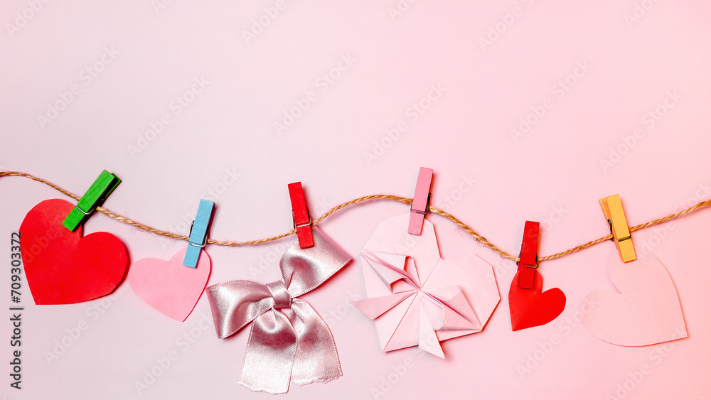 Decorations concept for Valentine's Day, Mother's Day. Top view photo of paper hearts hanging on wooden hooks against an isolated pastel pink background with space for text.......