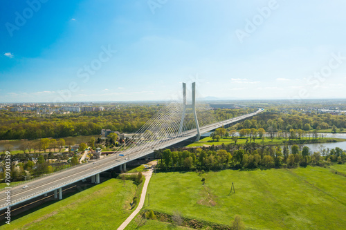 Famous cable-stayed Redzinski Bridge over blue flowing river among lush green forests. Scenic nature and urban infrastructure near Wroclaw aerial view