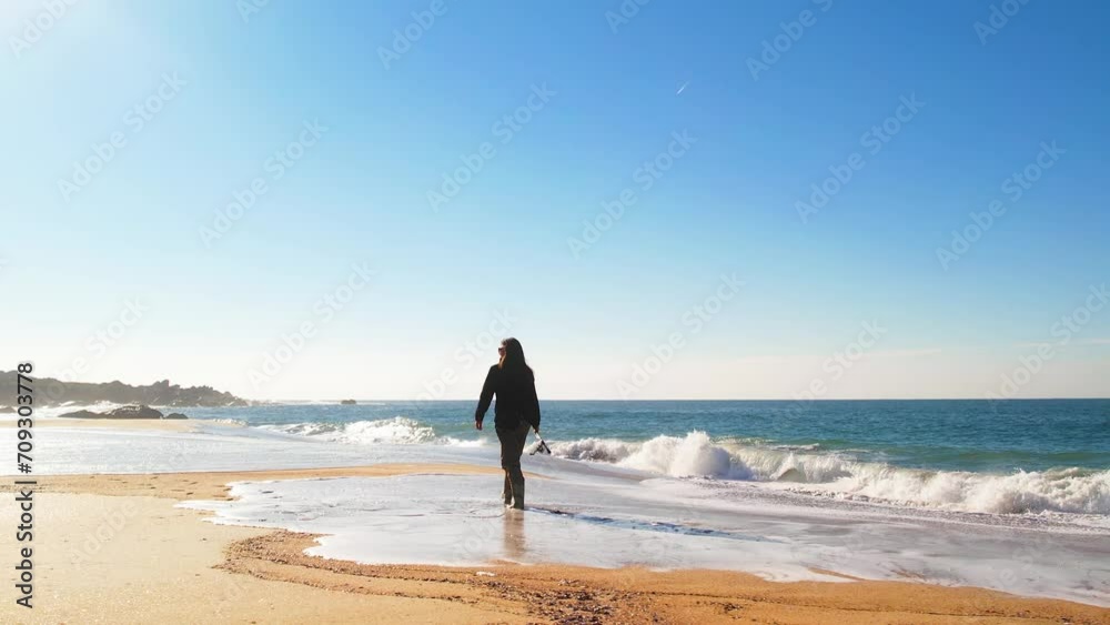 Fisherwoman walking on a beach, near the sea, with her fishing tackle Fisherwoman walking on a beach, near the sea, with her fishing tackle