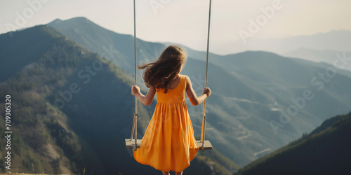 Little Girl Swinging On A Swing Against Mountain Landscape