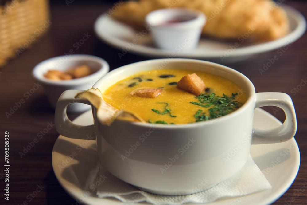 A cup of creamy pumpkin soup with croutons A cup of creamy pumpkin soup with croutons