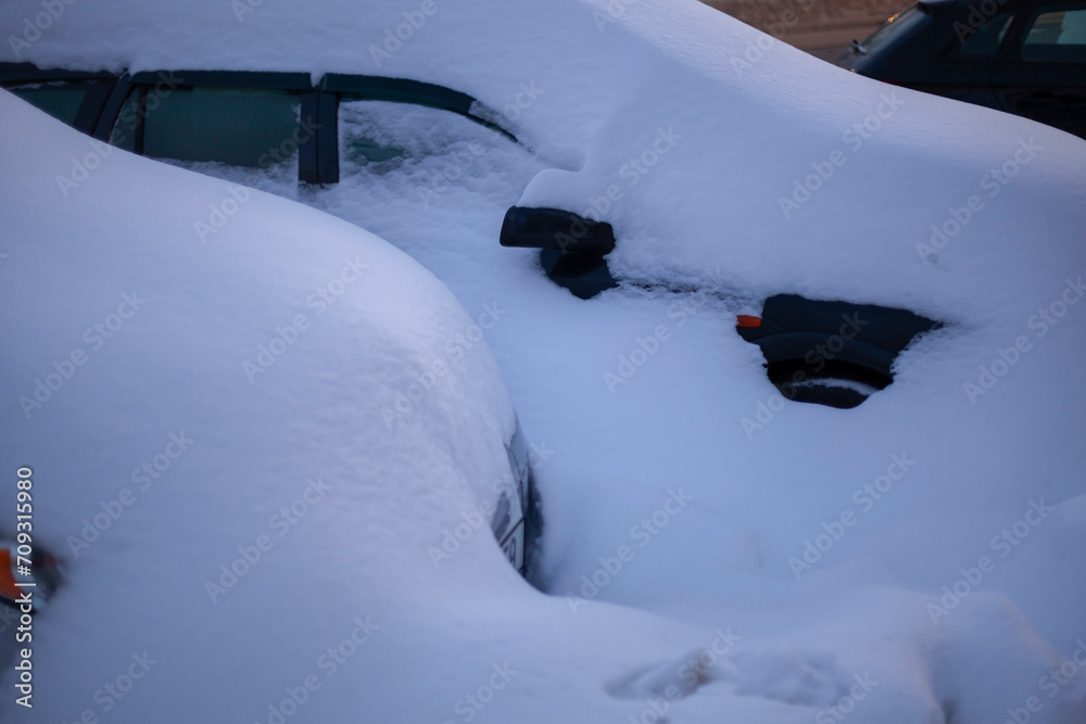 Winter parking. Cars under a layer of snow. Urban difficulties. Winter transport and transportation concept.