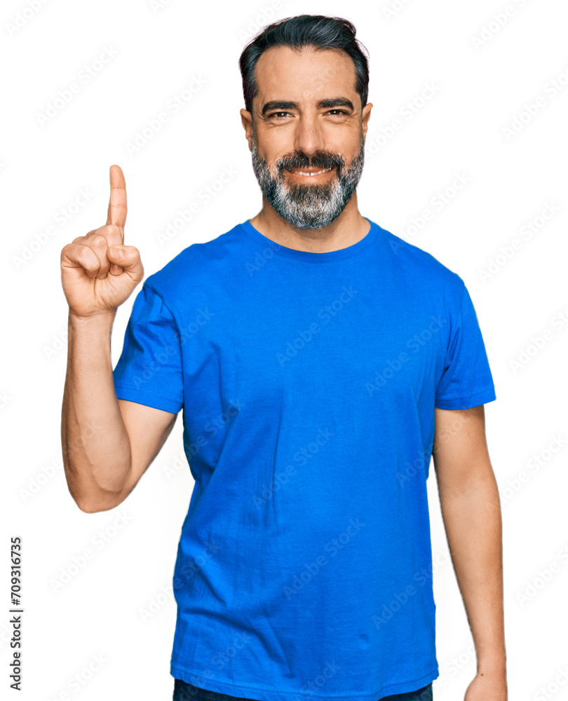 Middle aged man with beard wearing casual blue t shirt showing and pointing up with finger number one while smiling confident and happy. Middle aged man with beard wearing casual blue t shirt showing and pointing up with finger number one while smiling confident and happy.