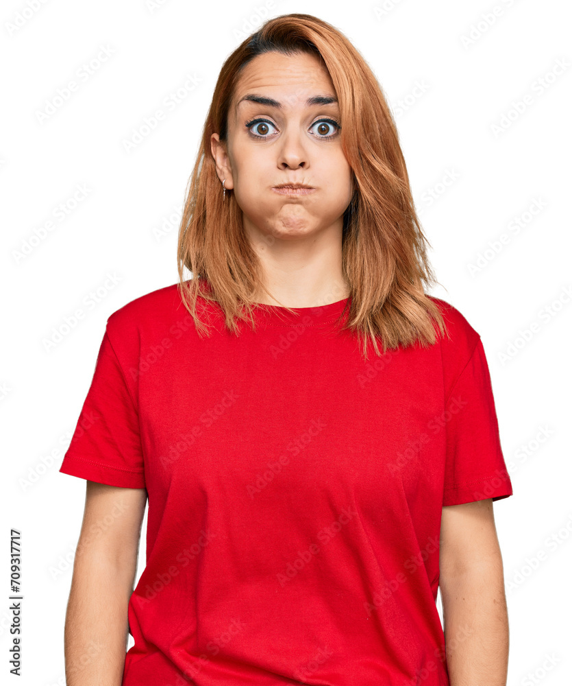 Fototapeta premium Hispanic young woman wearing casual red t shirt puffing cheeks with funny face. mouth inflated with air, crazy expression.