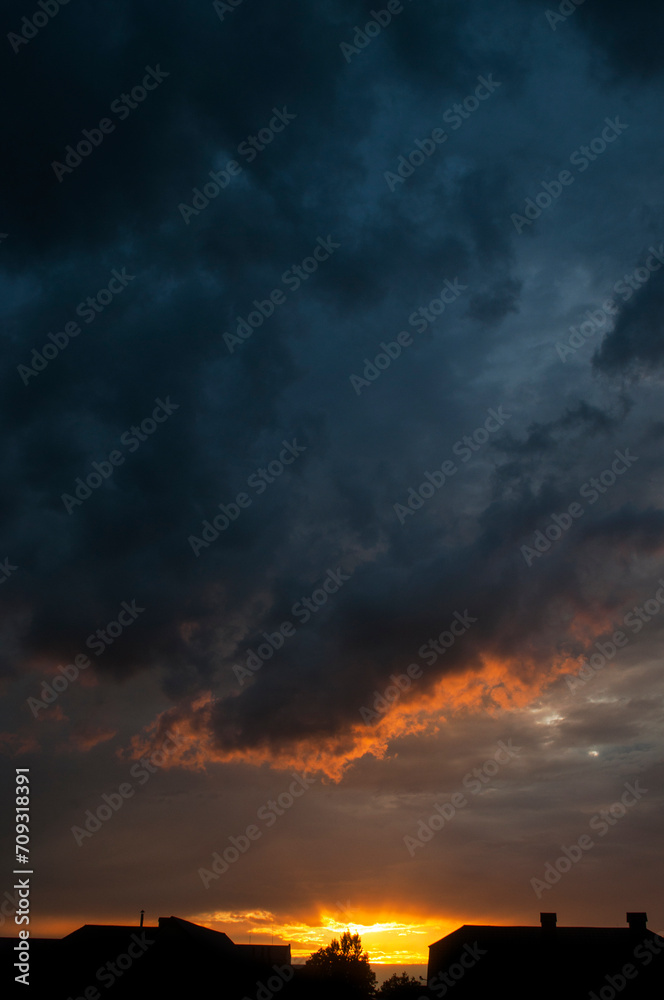 Abstract colorful background. Beautiful red sunset over a small town. Dramatic sunset sky with clouds.
