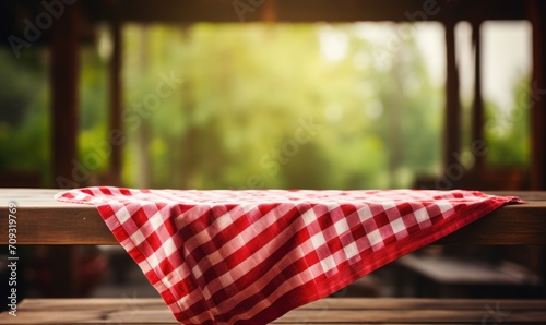 table covered with a white and red checkered tablecloth against the background of a window as a basis for the presentation of the subject photo
