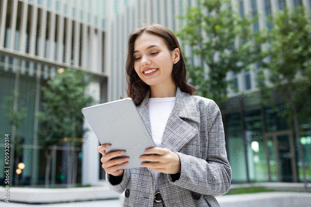 business lady happily browsing on digital tablet computer, standing outside