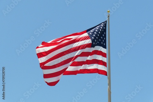 American flag waving in wind on blue sky background 