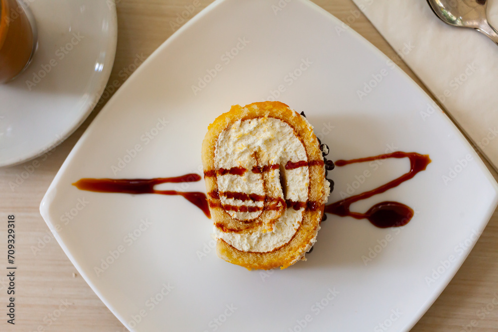 Fototapeta premium Delicious roll sponge cake with vanilla cream and chocolate sauce