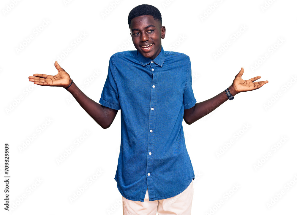 Naklejka premium Young african american man wearing casual clothes clueless and confused expression with arms and hands raised. doubt concept.