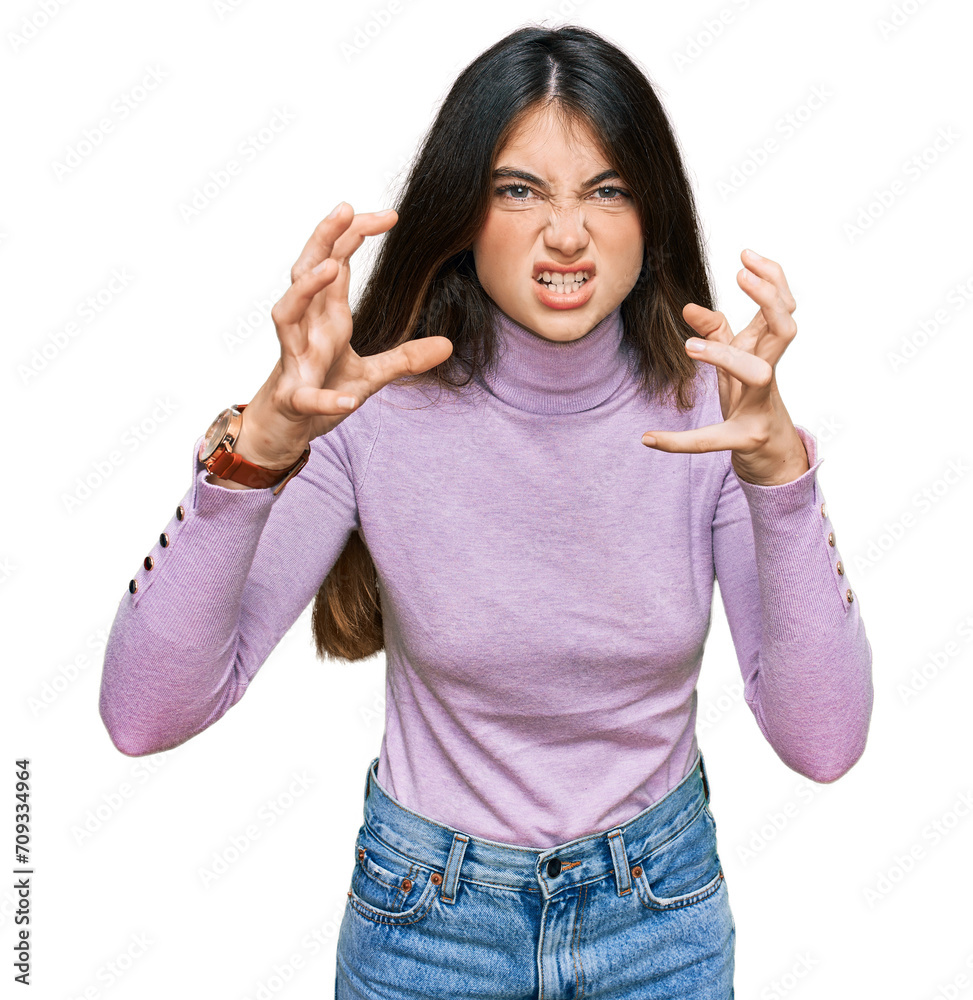 Young beautiful teen girl wearing turtleneck sweater shouting frustrated with rage, hands trying to strangle, yelling mad
