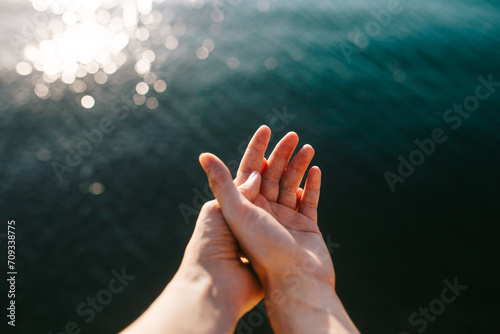 Sunlit hands over tranquil water backdrop photo