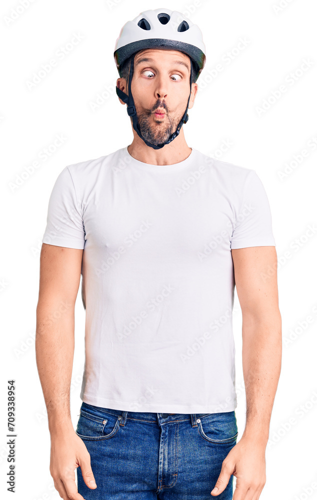 Young handsome man wearing bike helmet making fish face with lips, crazy and comical gesture. funny expression. Young handsome man wearing bike helmet making fish face with lips, crazy and comical gesture. funny expression.
