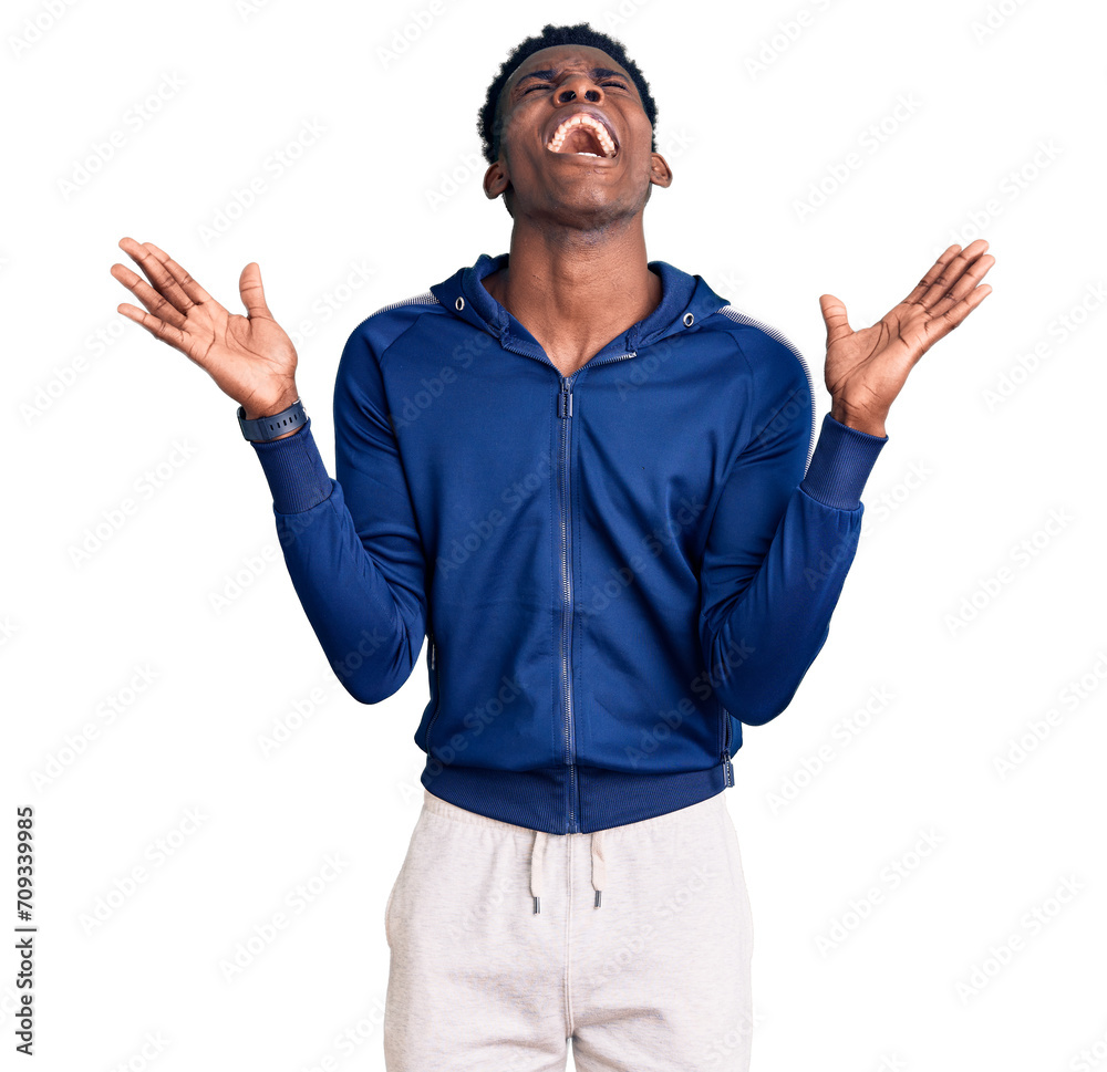 Young african american man wearing sportswear celebrating mad and crazy for success with arms raised and closed eyes screaming excited. winner concept Young african american man wearing sportswear celebrating mad and crazy for success with arms raised and closed eyes screaming excited. winner concept