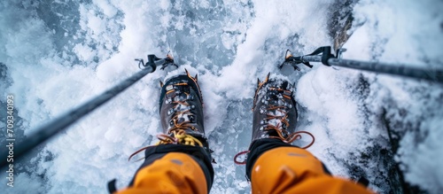 Professional image of climber's feet in crampons and using trekking poles, seen from above. photo