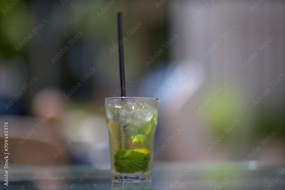 Refreshing green lemonade in a glass on the table against the background of nature. Freshly squeezed drinks with ice. Lemonade with lemon, mint lime and herbs Refreshing green lemonade in a glass on the table against the background of nature. Freshly squeezed drinks with ice. Lemonade with lemon, mint lime and herbs