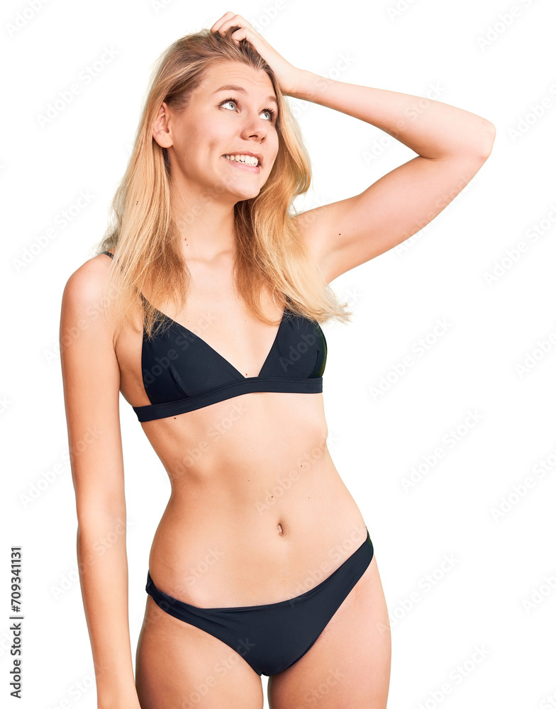 Young beautiful blonde woman wearing bikini smiling confident touching hair with hand up gesture, posing attractive and fashionable Young beautiful blonde woman wearing bikini smiling confident touching hair with hand up gesture, posing attractive and fashionable