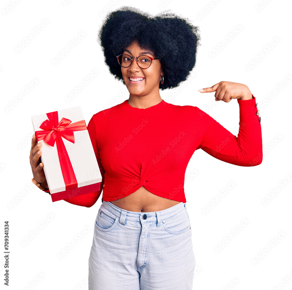 Young african american girl holding gift looking confident with smile on face, pointing oneself with fingers proud and happy. Young african american girl holding gift looking confident with smile on face, pointing oneself with fingers proud and happy.