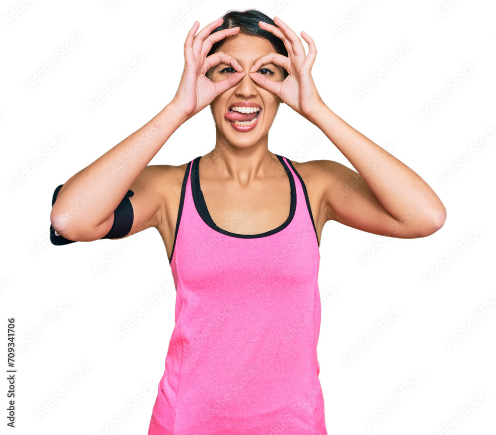 Beautiful asian young sport woman wearing sportswear and arm band doing ok gesture like binoculars sticking tongue out, eyes looking through fingers. crazy expression. Beautiful asian young sport woman wearing sportswear and arm band doing ok gesture like binoculars sticking tongue out, eyes looking through fingers. crazy expression.