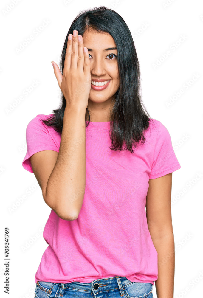 Beautiful asian young woman wearing casual pink t shirt covering one eye with hand, confident smile on face and surprise emotion. Beautiful asian young woman wearing casual pink t shirt covering one eye with hand, confident smile on face and surprise emotion.