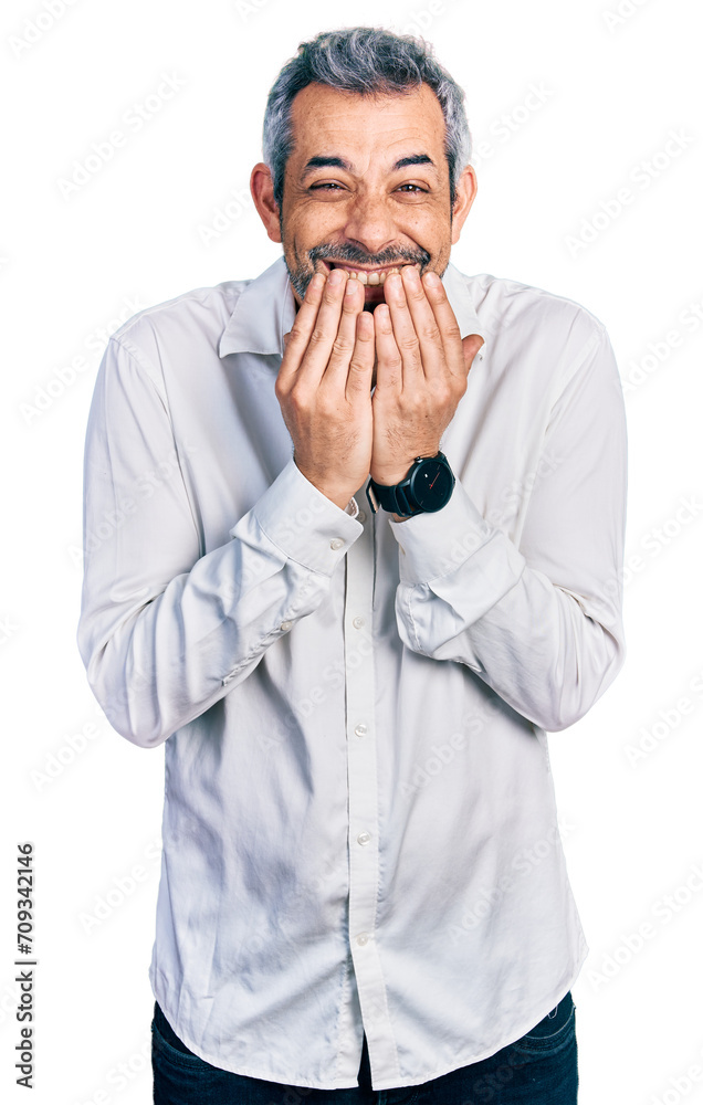 Middle age hispanic with grey hair wearing casual white shirt laughing and embarrassed giggle covering mouth with hands, gossip and scandal concept Middle age hispanic with grey hair wearing casual white shirt laughing and embarrassed giggle covering mouth with hands, gossip and scandal concept