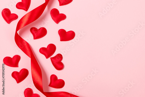 Red silk ribbon and hearts on a pink background. Valentine's day, place for text.