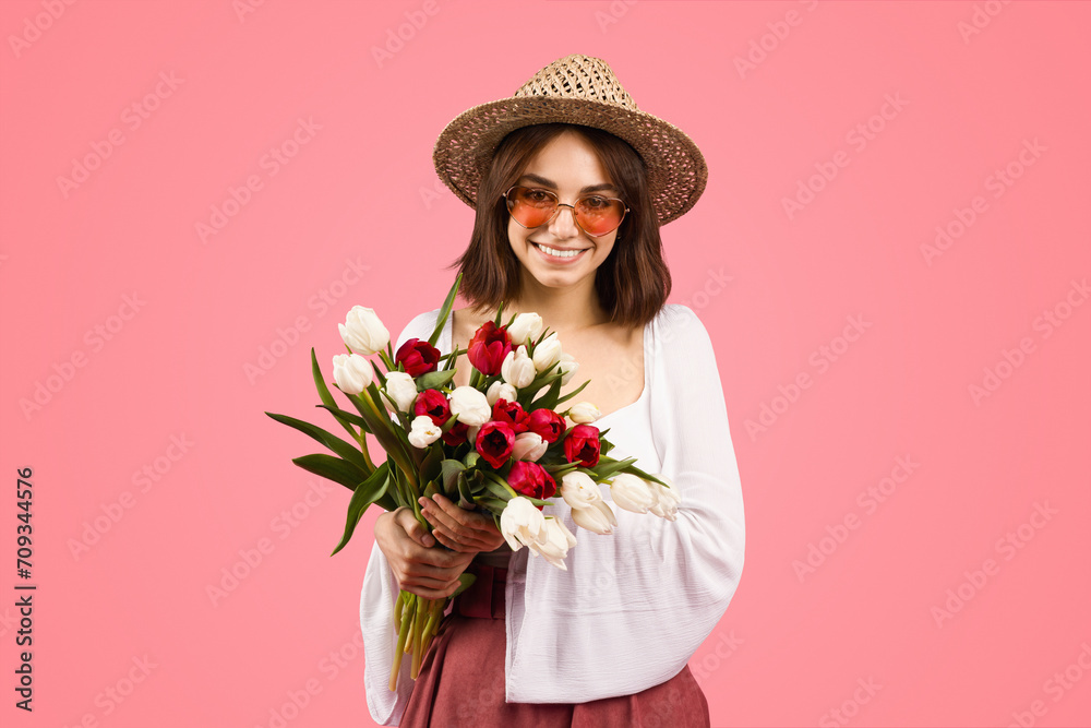 Radiant young woman with a joyful smile, wearing a straw hat and round sunglasses Radiant young woman with a joyful smile, wearing a straw hat and round sunglasses