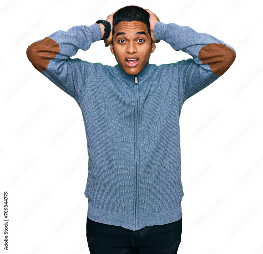 Young handsome hispanic man wearing casual sweatshirt crazy and scared with hands on head, afraid and surprised of shock with open mouth Young handsome hispanic man wearing casual sweatshirt crazy and scared with hands on head, afraid and surprised of shock with open mouth