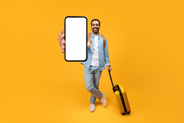 Happy indian man traveler in casual with yellow suitcase, enjoy adventure, show phone with empty screen