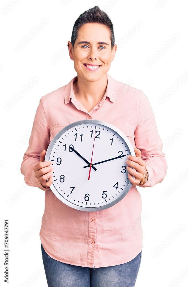 Young woman with short hair holding big clock looking positive and happy standing and smiling with a confident smile showing teeth Young woman with short hair holding big clock looking positive and happy standing and smiling with a confident smile showing teeth