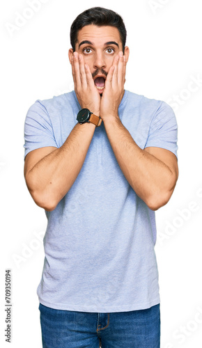 Young hispanic man wearing casual clothes afraid and shocked  surprise and amazed expression with hands on face