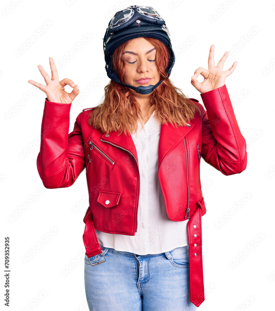 Young latin woman wearing leather jacket holding motorcycle helmet relax and smiling with eyes closed doing meditation gesture with fingers. yoga concept. Young latin woman wearing leather jacket holding motorcycle helmet relax and smiling with eyes closed doing meditation gesture with fingers. yoga concept.