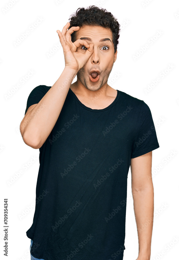 Young handsome man wearing casual black t shirt doing ok gesture shocked with surprised face, eye looking through fingers. unbelieving expression. Young handsome man wearing casual black t shirt doing ok gesture shocked with surprised face, eye looking through fingers. unbelieving expression.