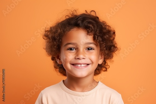 Portrait of a smiling little african american girl over orange background © Igor