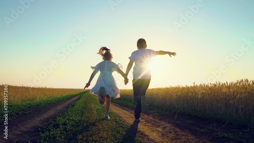 Child, nature vacation. Childhood dream concept, Carefree child in summer. Kids boy girl play fun run holding hands. Children in together run through wheat field at sunset. Happy family. Farmer child