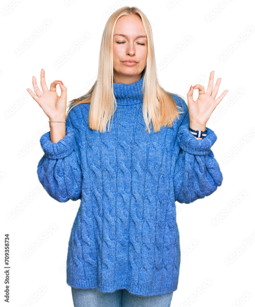 Young blonde girl wearing wool winter sweater relax and smiling with eyes closed doing meditation gesture with fingers. yoga concept. Young blonde girl wearing wool winter sweater relax and smiling with eyes closed doing meditation gesture with fingers. yoga concept.