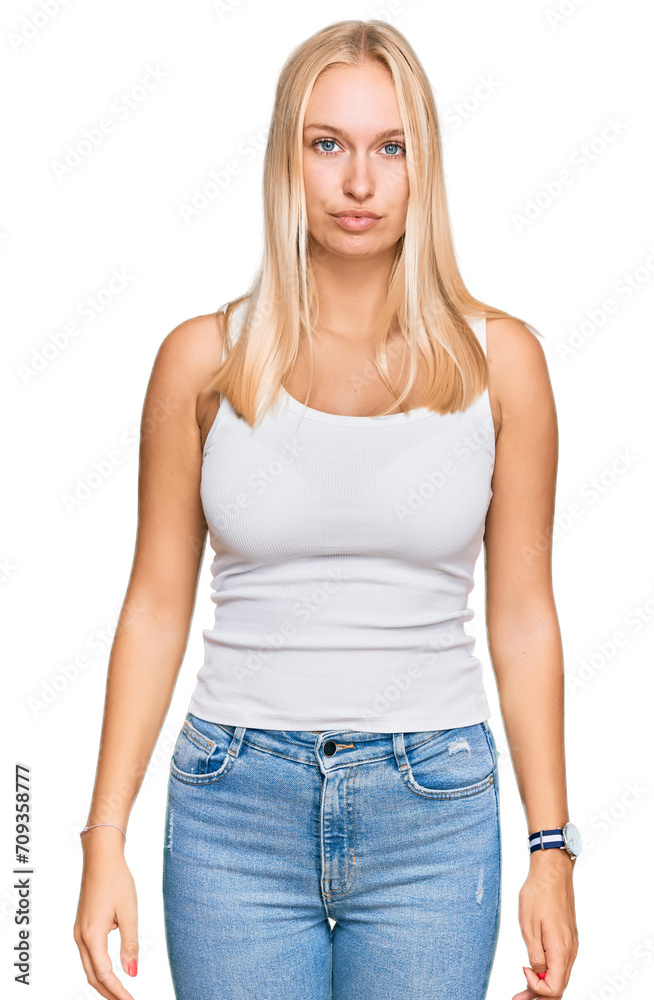 Young blonde girl wearing casual style with sleeveless shirt relaxed with serious expression on face. simple and natural looking at the camera. Young blonde girl wearing casual style with sleeveless shirt relaxed with serious expression on face. simple and natural looking at the camera.