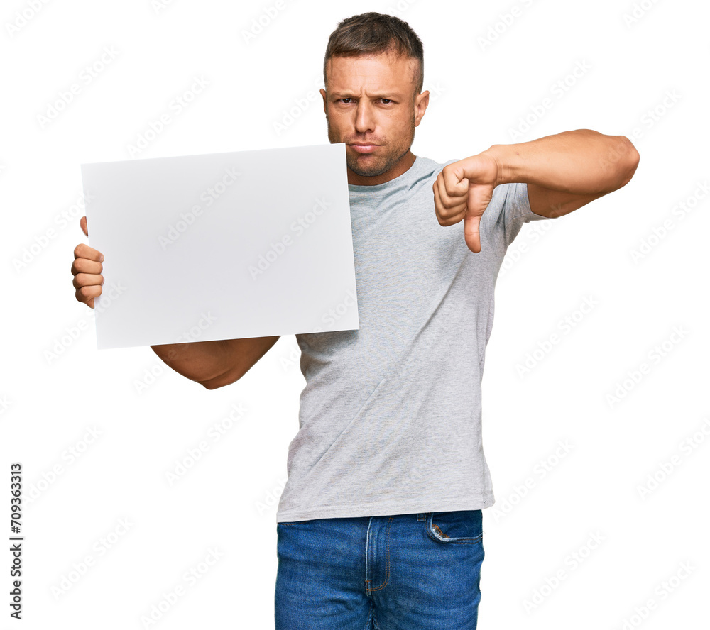 Handsome muscle man holding blank empty banner with angry face, negative sign showing dislike with thumbs down, rejection concept Handsome muscle man holding blank empty banner with angry face, negative sign showing dislike with thumbs down, rejection concept