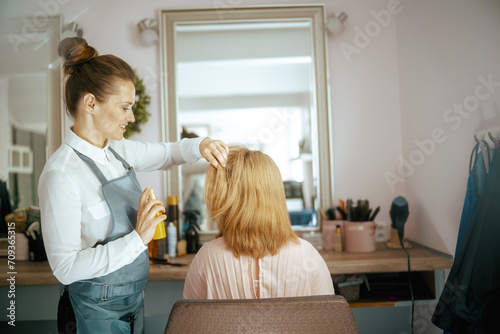 female hairdresser in modern beauty salon with hair spray