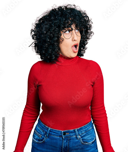Fotografie Young middle east girl wearing casual clothes and glasses in shock face, looking