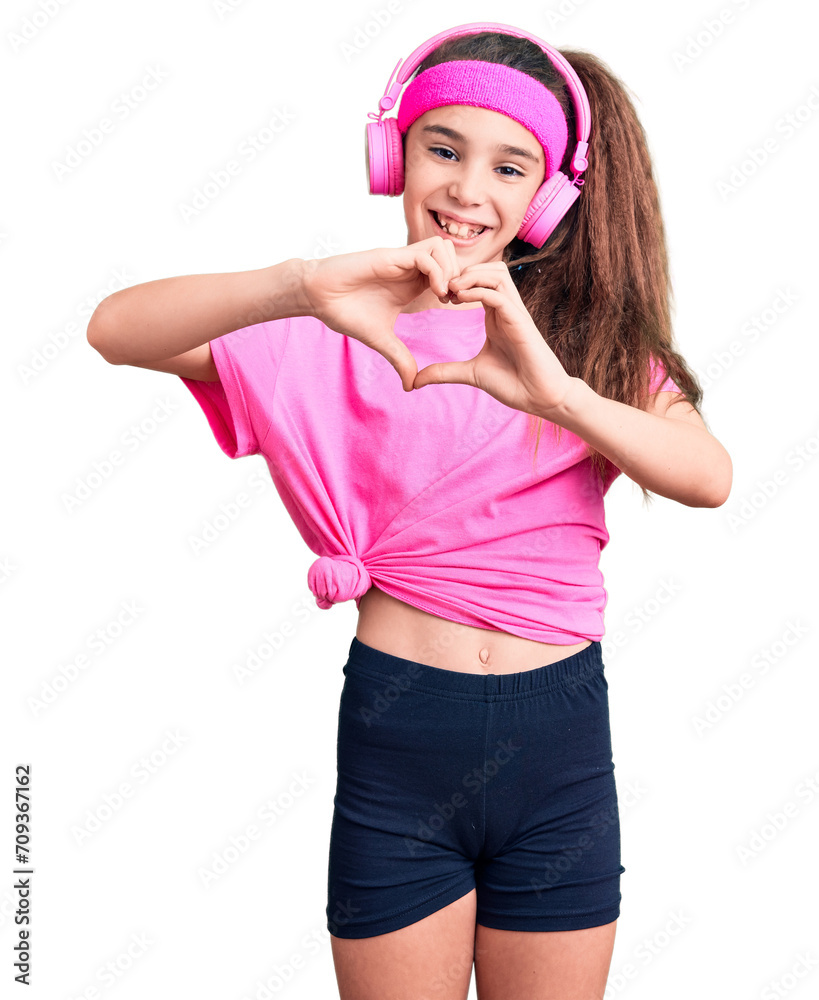 Cute hispanic child girl wearing gym clothes and using headphones smiling in love doing heart symbol shape with hands. romantic concept. Cute hispanic child girl wearing gym clothes and using headphones smiling in love doing heart symbol shape with hands. romantic concept.